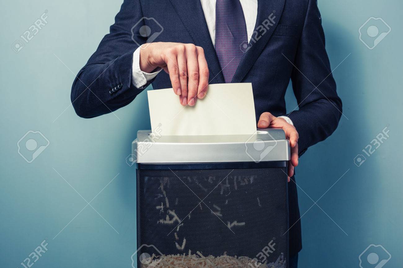 businessman shredding important documents. paper shredder. man in suit. document disposal